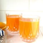 Glass of carrot orange juice on the counter.