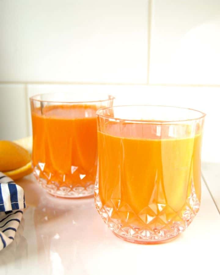 Glass of carrot orange juice on the counter.