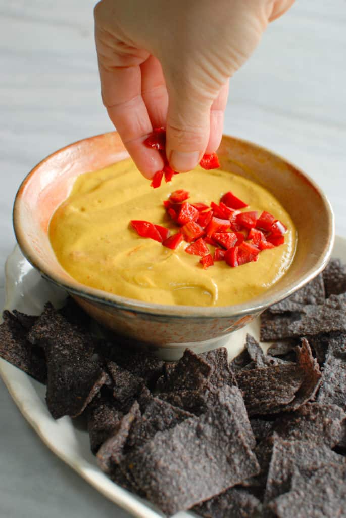 a bowl of savory pumpkin dip topped with red bell pepper pieces