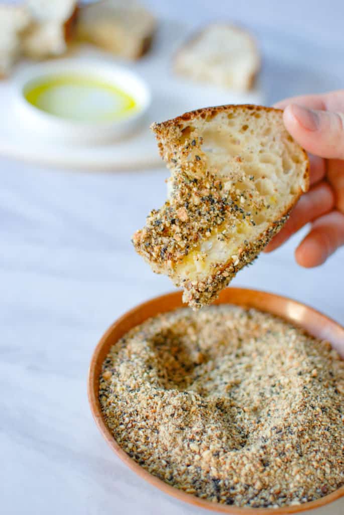a piece of bread coated with dukkah spices and olive oil.