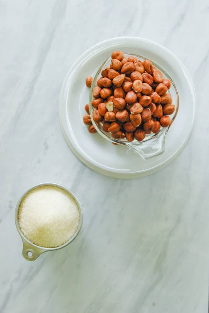 1 cup of hazelnuts and 1 cup of sugar on a counter, the ingredients for orgeat syrup.