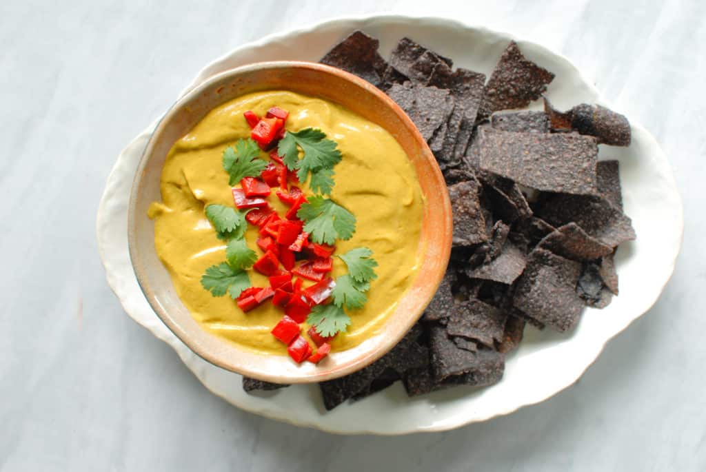 vegan pumpkin queso in a bowl next to tortilla chips.