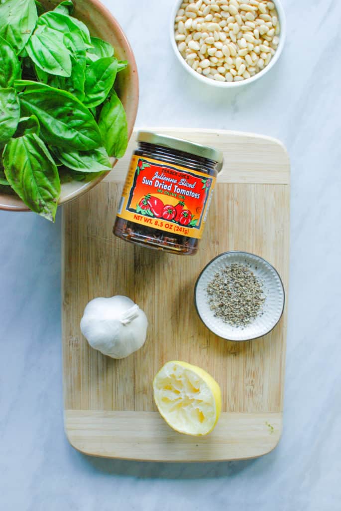 ingredients for vegan sundried tomato pesto on a cutting board