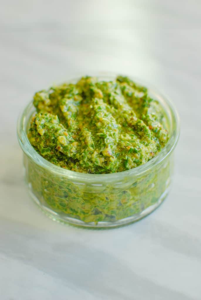 Fresh homemade walnut pesto in a dish on the counter.