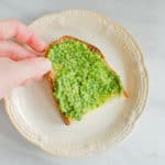 A piece of toast slathered with vegan nut-free pesto.