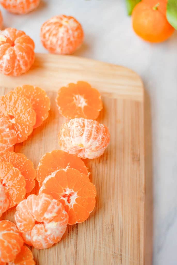 sliced clementines on a cutting board, to use in a clementine upside down cake.