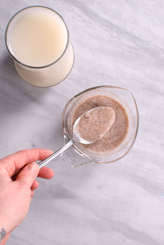 A glass of flax milk next to a flax egg.