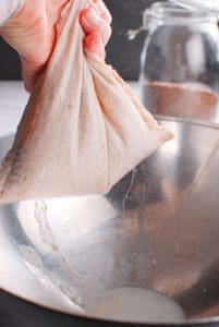 a hand squeezing the pulp out of flaxseed milk