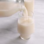 A jug pouring flaxseed milk into a glass