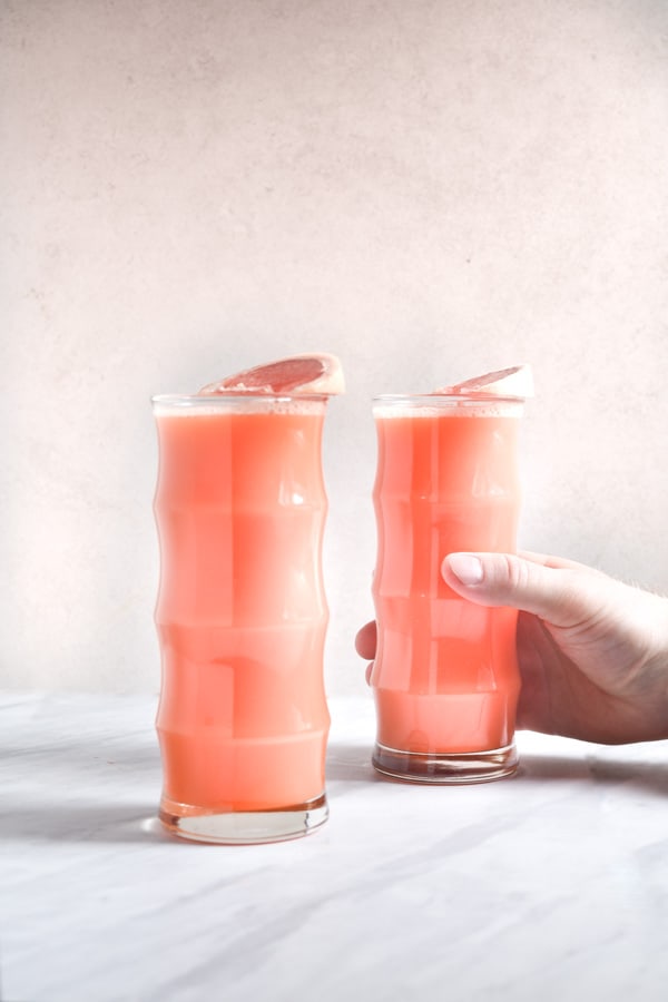 hand reaching for a glass of grapefruit juice