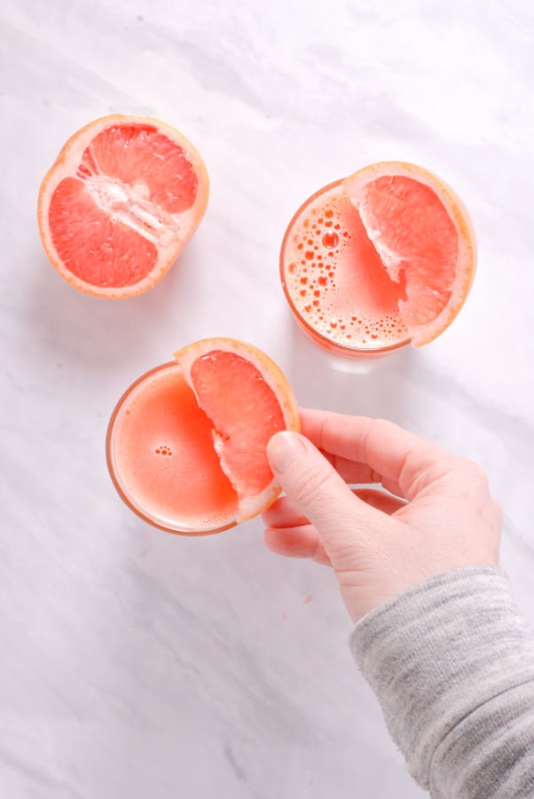 a hand reaching for a grapefruit