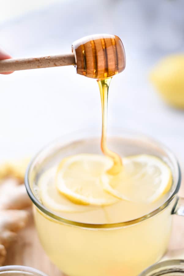 Honey drizzling into a mug of lemon ginger tea