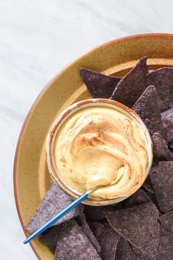 a bowl of vegan tofu queso dip with chips next to it