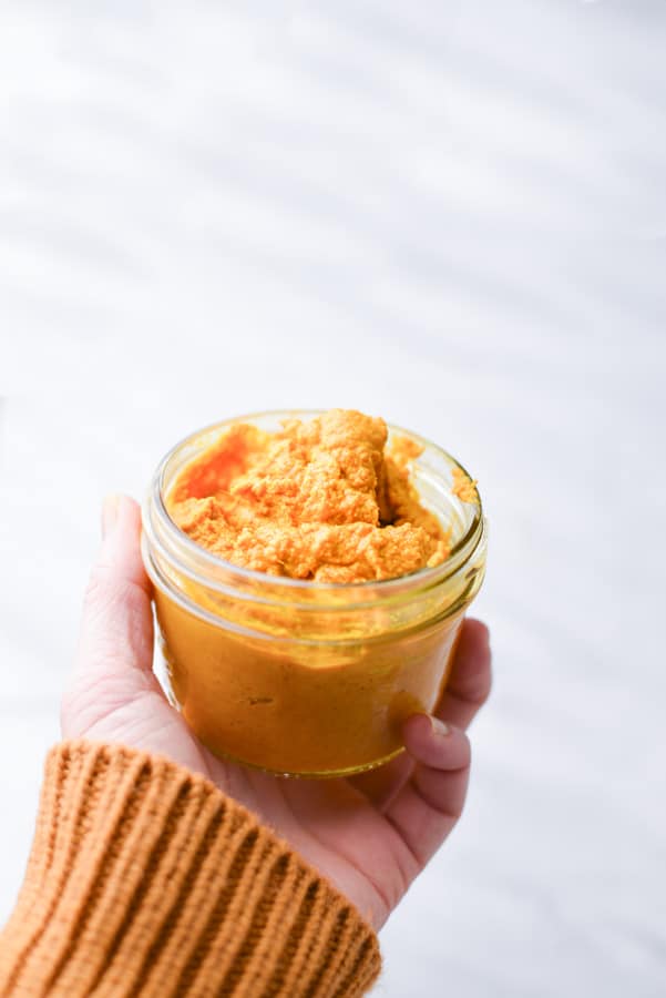 hand holding a jar of golden turmeric paste