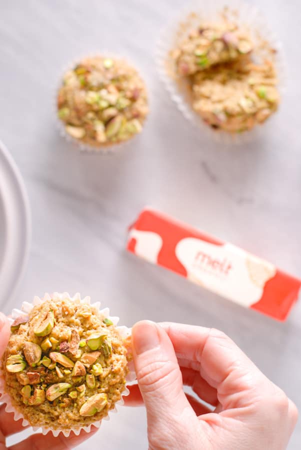 a hand holding a fresh pistachio muffin