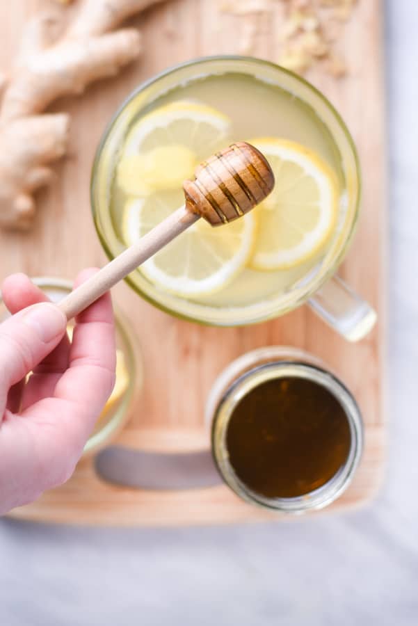 fresh ginger and a jar of honey next to a cup of tea