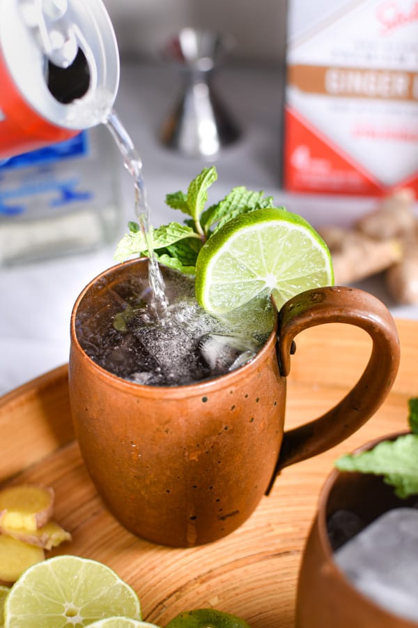 pouring ginger beer into a mexican mule drink