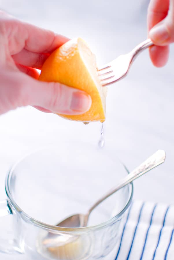 two hands juicing a lemon with a fork