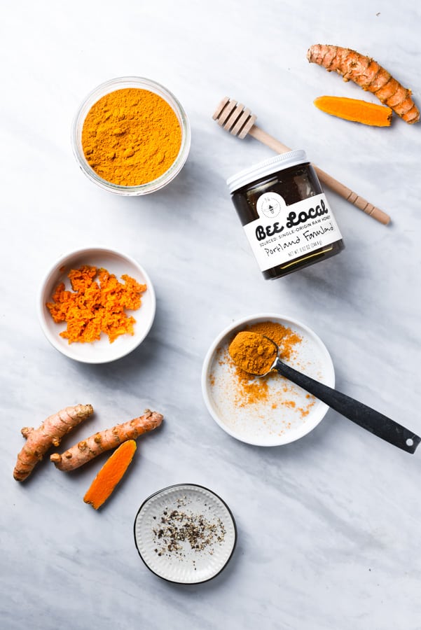 powdered turmeric, fresh turmeric, and honey on a counter