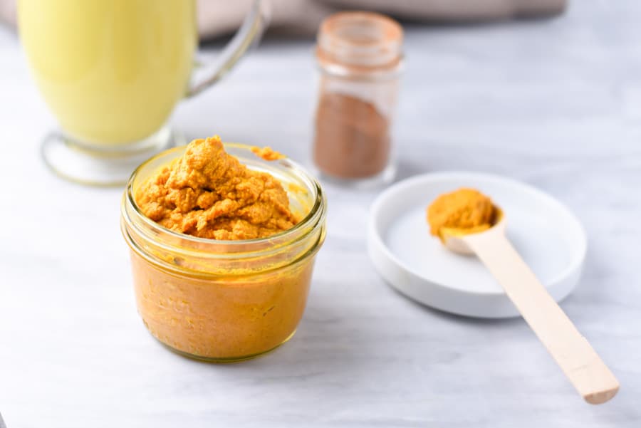 turmeric paste on the counter, next to a golden milk latte