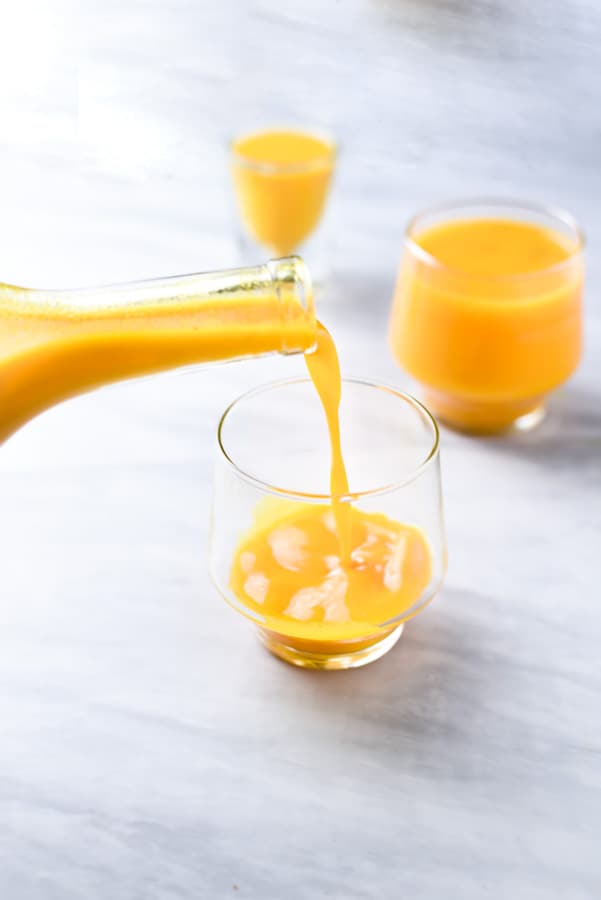 Pouring fresh turmeric juice into a glass