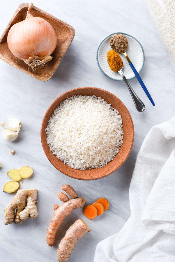 all the ingredient to make turmeric rice on a marble board