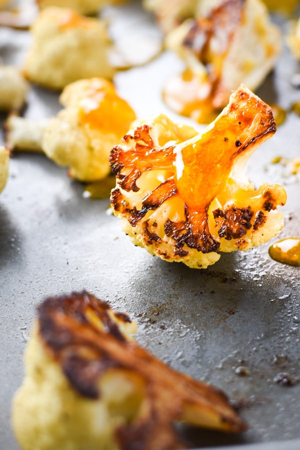 Close up of orange sauce dripping over cauliflower pieces