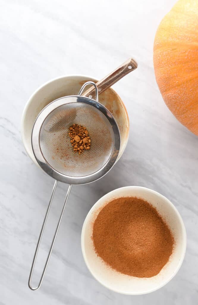 A sifter showing spices clumped together while making pumpkin pie spice.