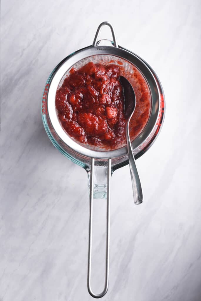 Straining strawberry syrup through a sieve