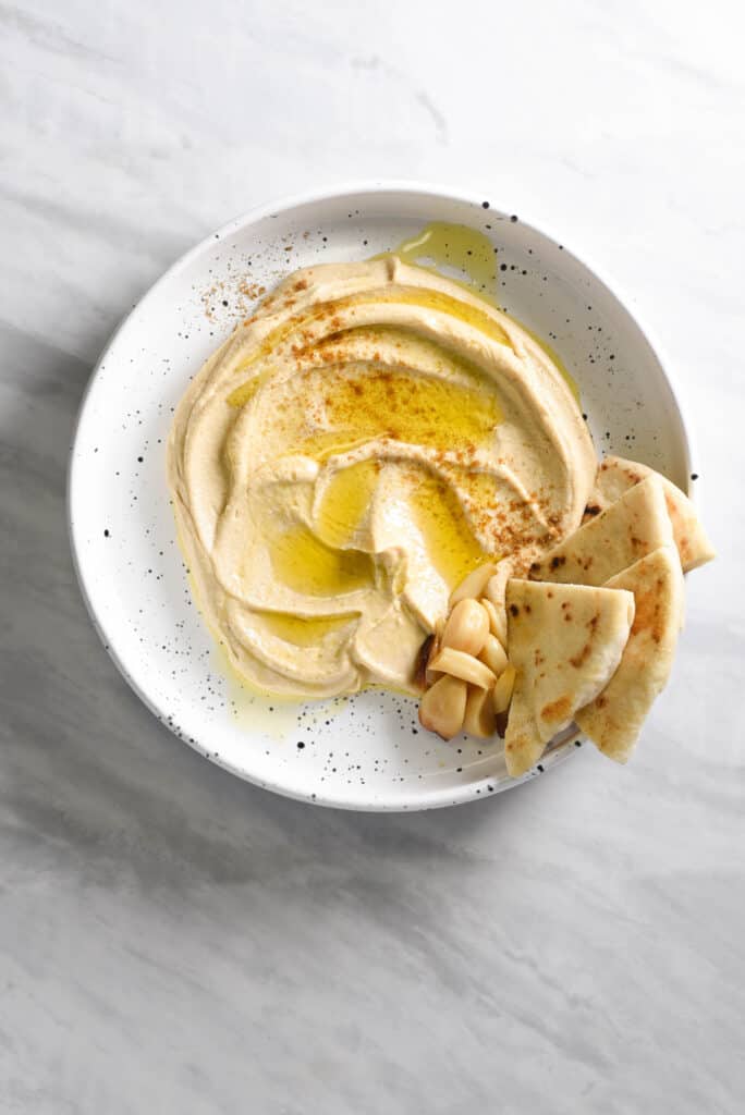 roasted garlic hummus on a platter with pita bread