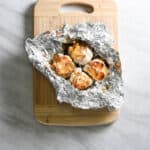 Whole heads of roasted garlic in aluminum foil