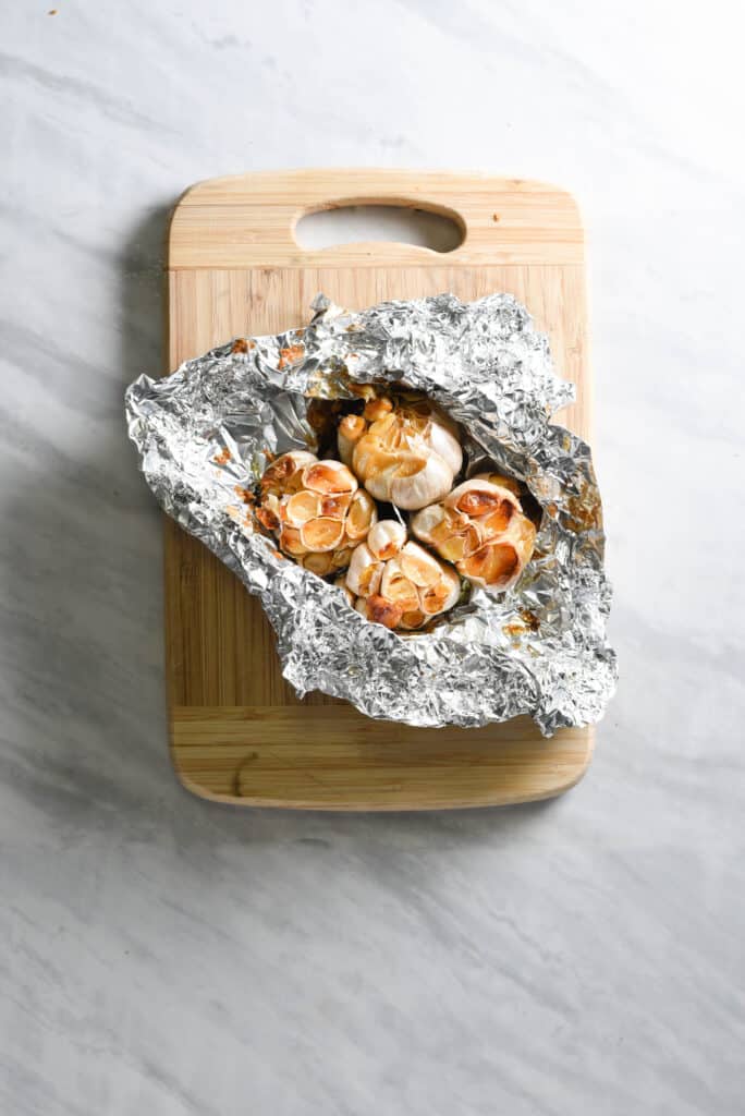 Whole heads of roasted garlic in aluminum foil