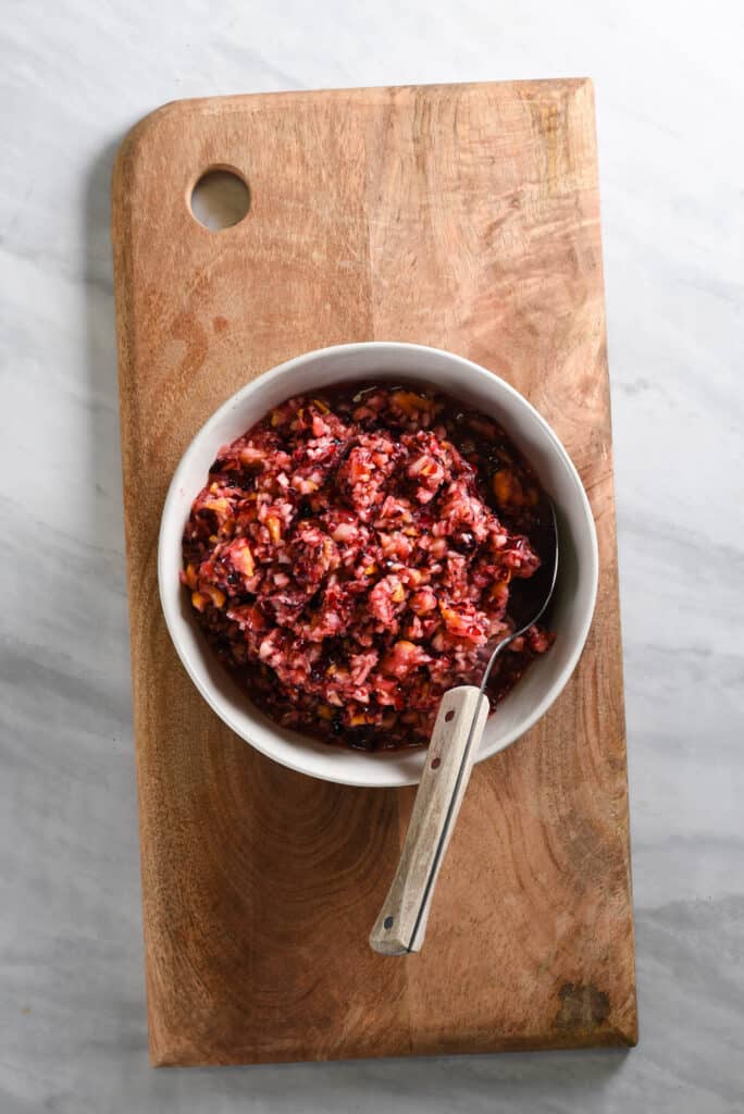 a bowl of the best cranberry relish on a cutting board