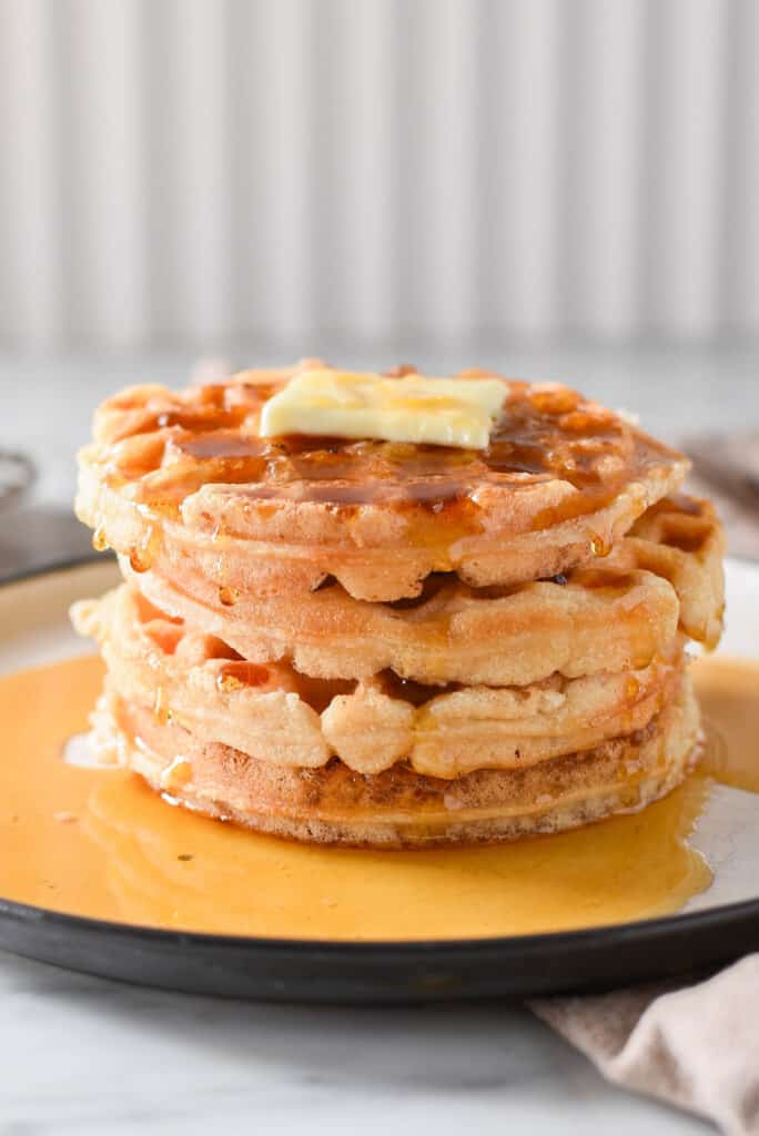 A tall stack of homemade fluffy vegan waffles on the counter.