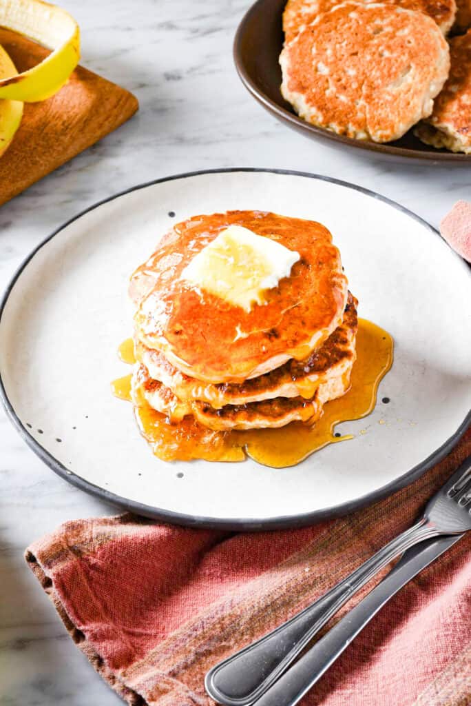 Vegan banana pancakes on a plate with butter and maple syrup